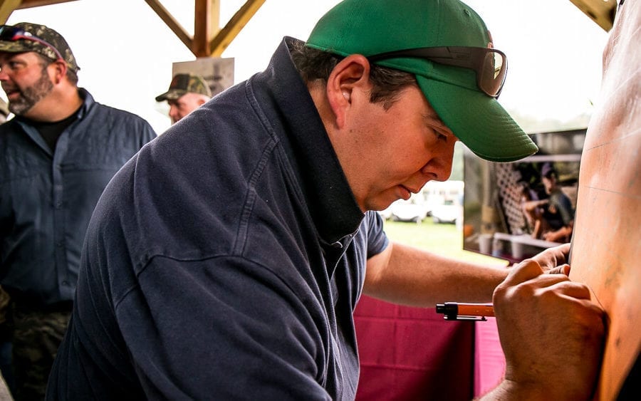 Man carving wooden panel at outdoor event