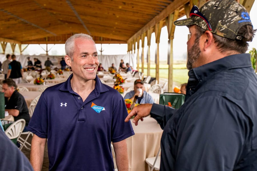 Two men talking under pavilion at outdoor event