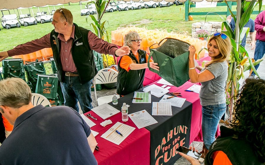 Outdoor event volunteers distributing tote bags at registration