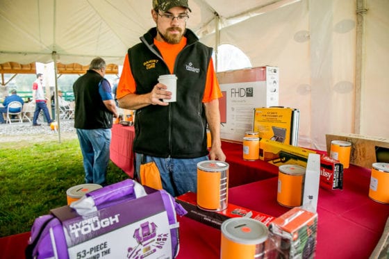 Man holding coffee near raffle prizes under tent