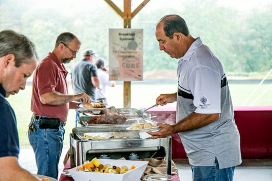 Men serving themselves at outdoor buffet