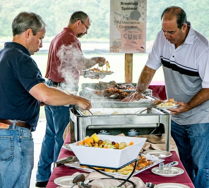 People serving themselves at outdoor buffet