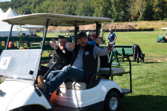 Two men waving from golf cart