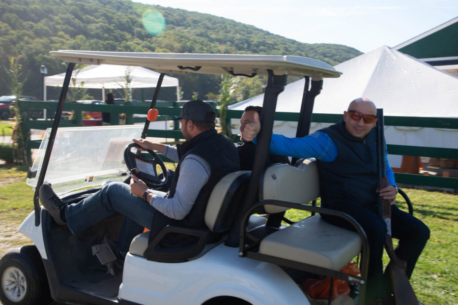 Three men riding in golf cart outdoors
