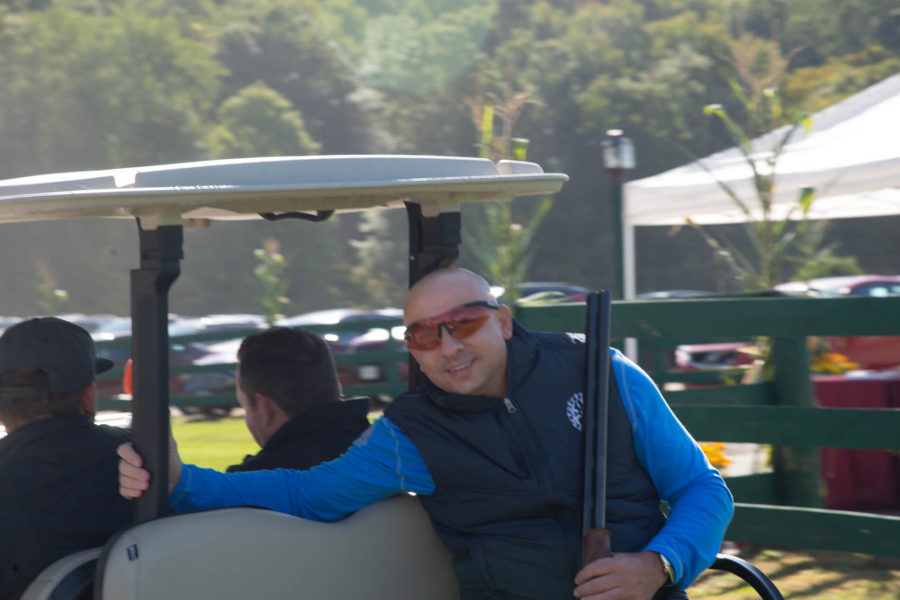 Smiling man holding shotgun on golf cart