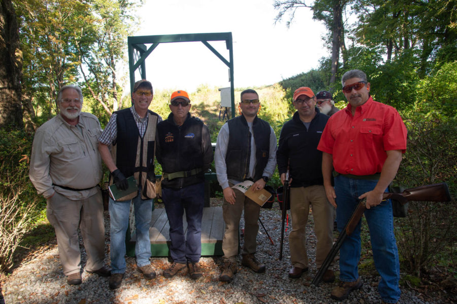 Men posing with shotguns outdoors