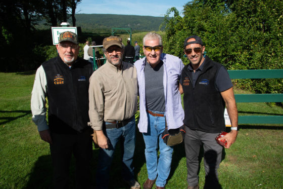 Four smiling men posing outdoors on grass