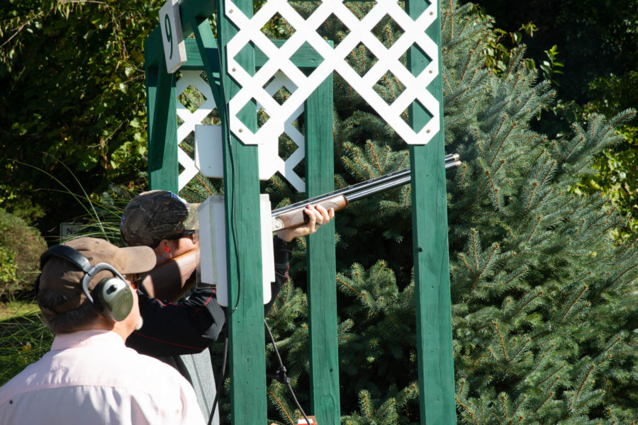 Shooter aiming shotgun from green shooting stand