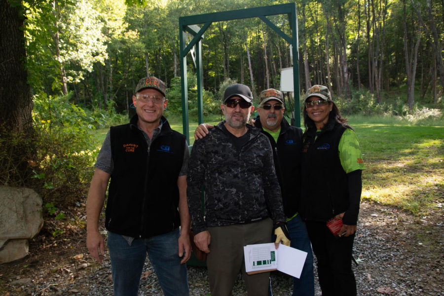 Four people posing outdoors near wooded area