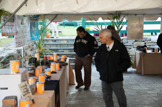 Two men browsing booths under white tent