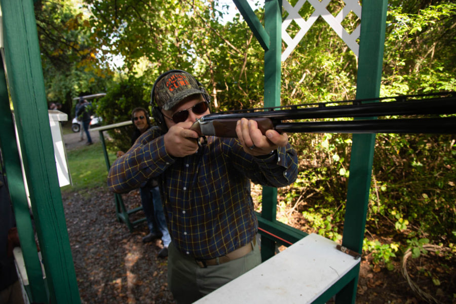 Person shooting shotgun at outdoor skeet range