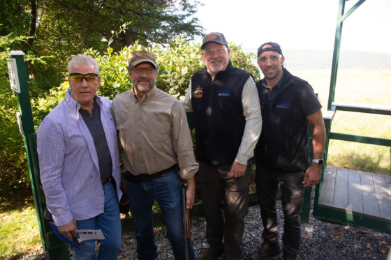 Four men standing outdoors near shooting range