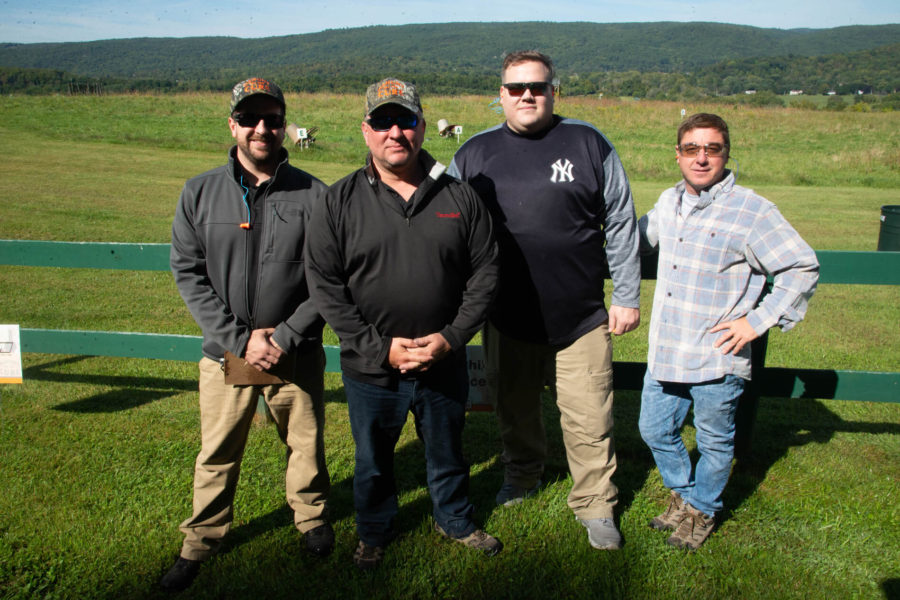 Four men standing in sunny grassy field
