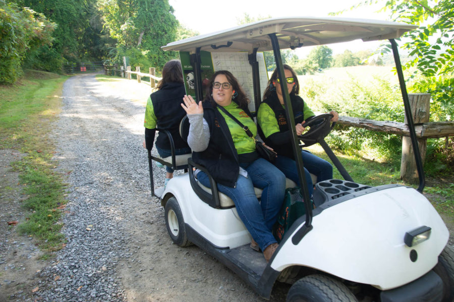 Three people in golf cart on gravel road