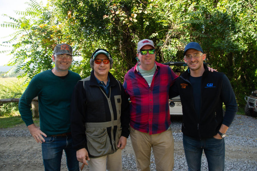 Four men outdoors wearing caps and sunglasses