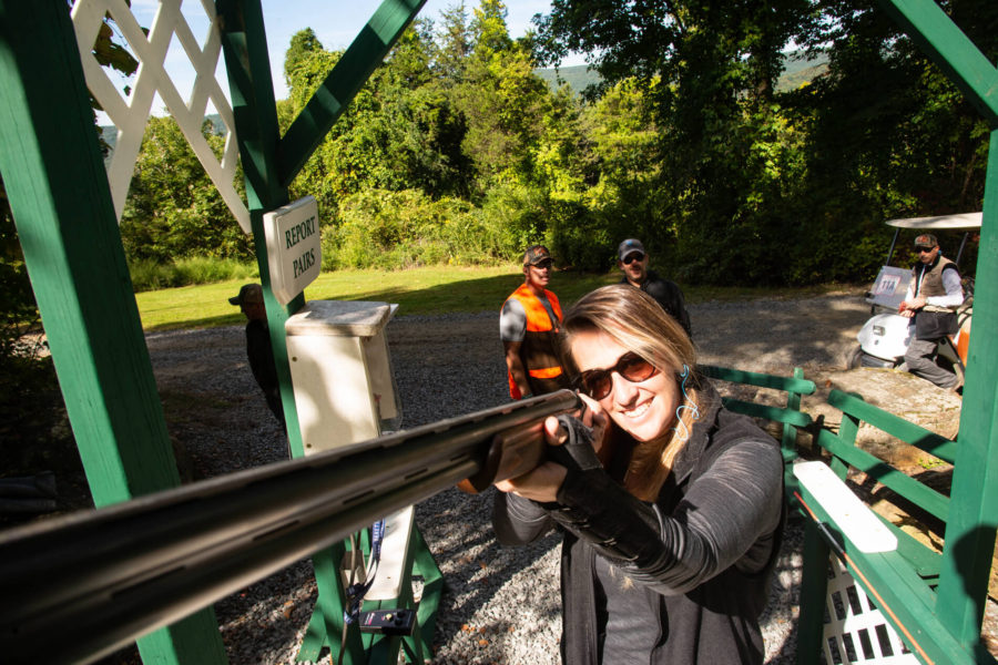 Smiling woman aiming shotgun at outdoor shooting range