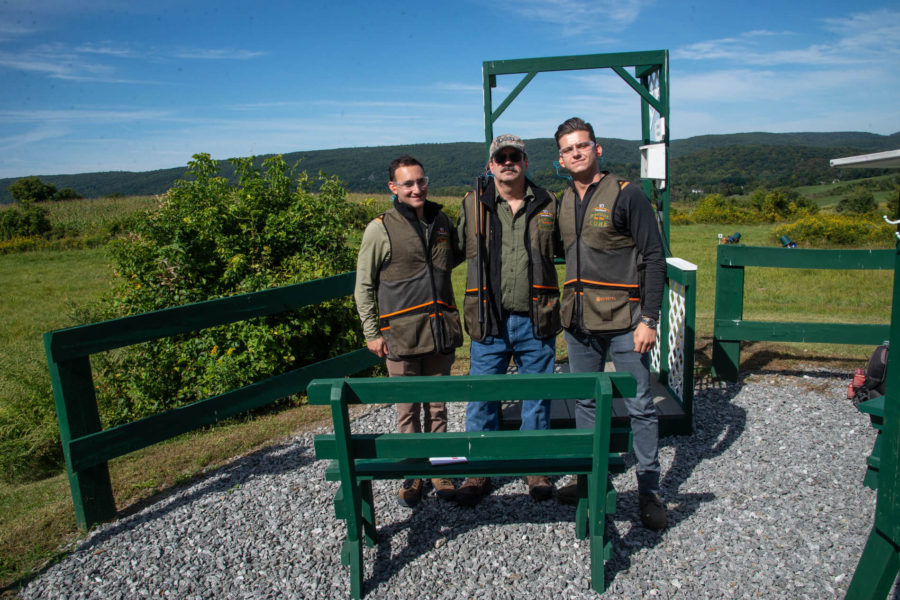 Three men posing at outdoor shooting range