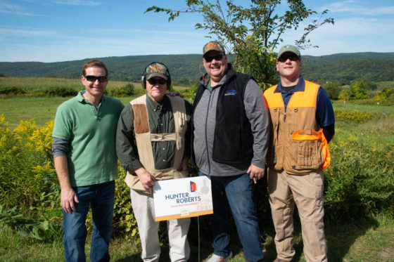 Four men smiling in field wearing hunting vests