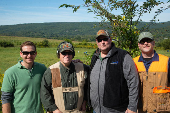 Four men in field wearing hunting gear