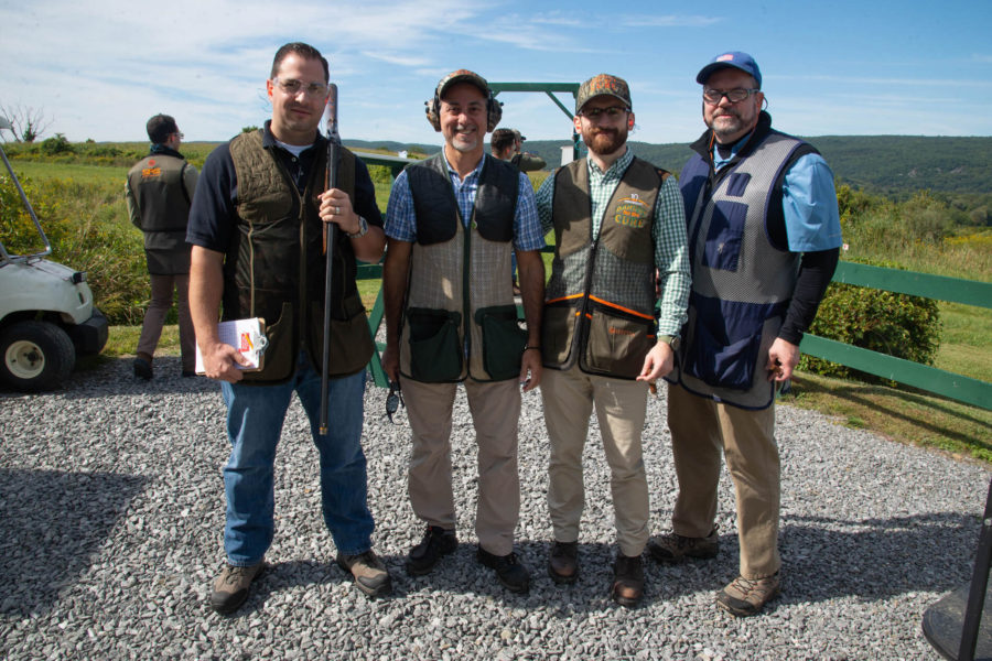 Four men wearing shooting vests outdoors