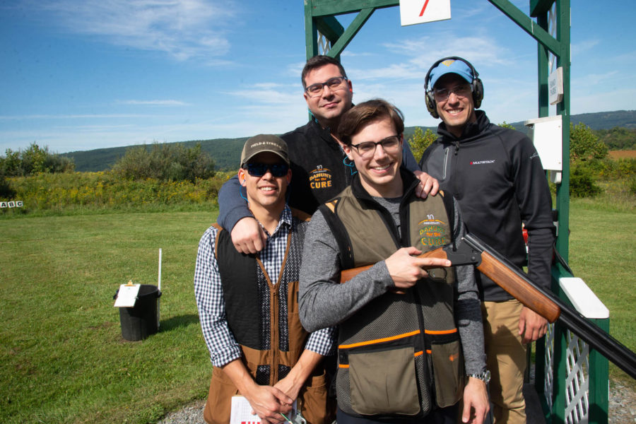 Four clay target shooters posing with shotgun