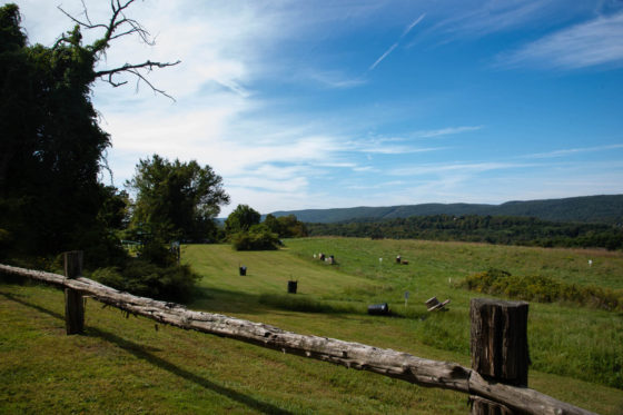 Wooden fence overlooking green pasture and hills