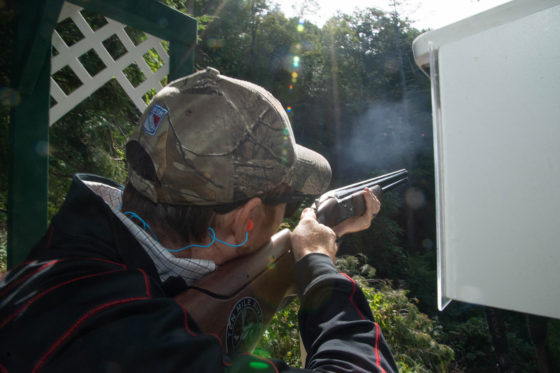 Person aiming shotgun at outdoor shooting range