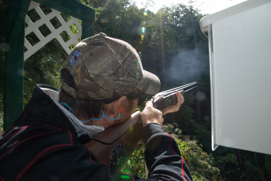 Person aiming shotgun at outdoor shooting range