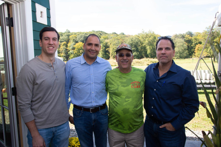 Four smiling men standing outdoors with trees