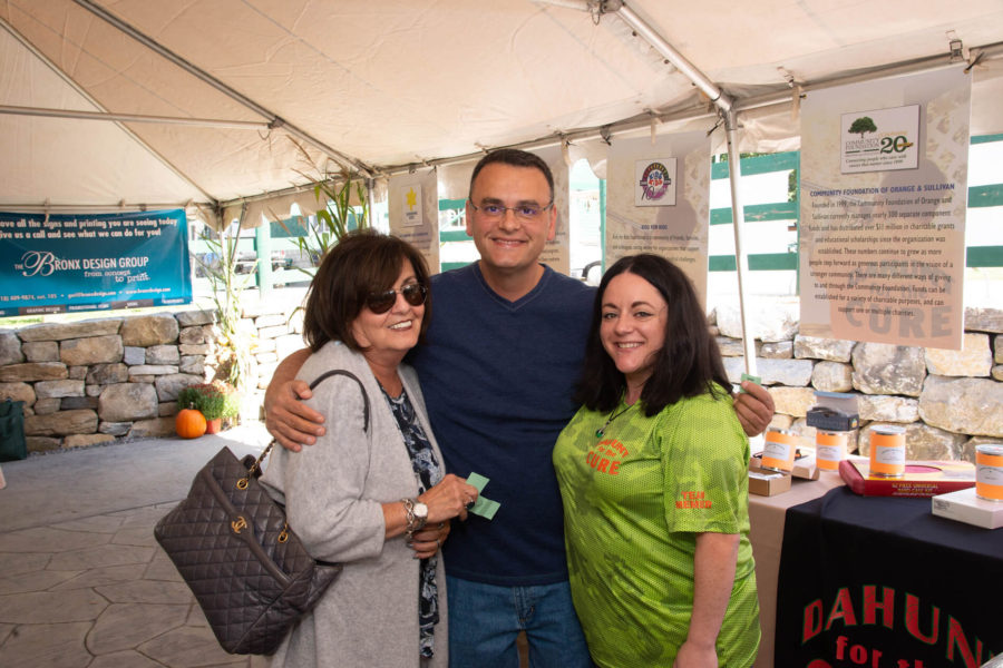 Three people smiling together at outdoor tent