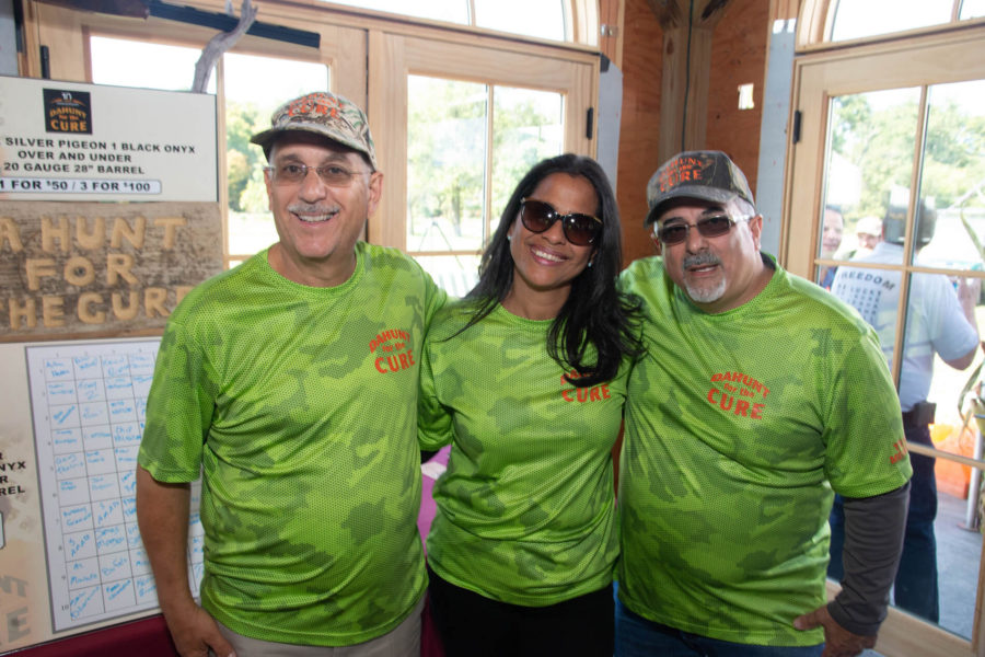 Three smiling people in matching green shirts