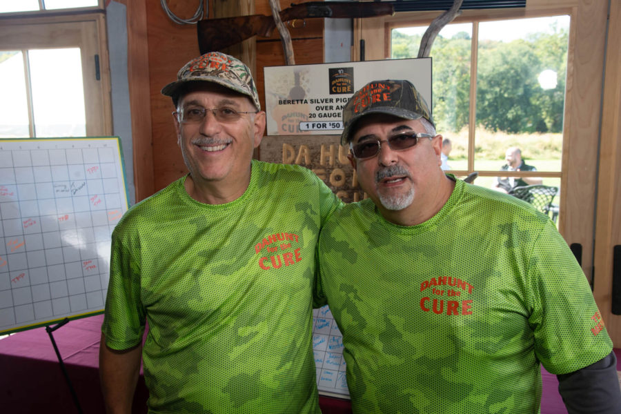 Two men in matching green shirts smiling