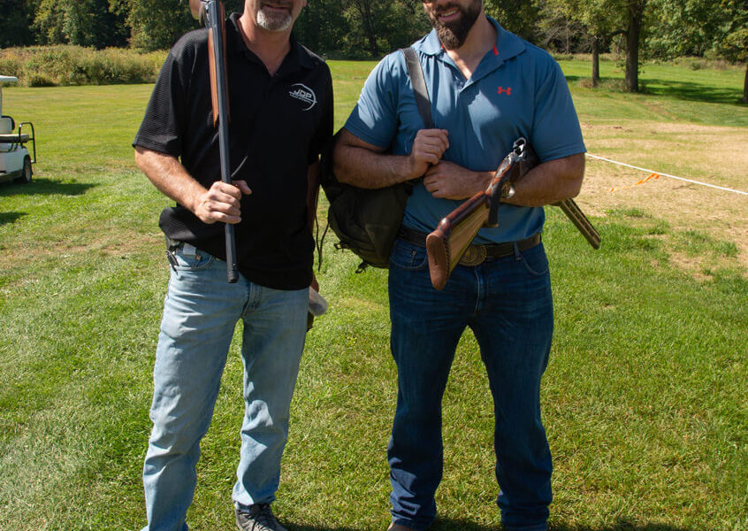 Two men with shotguns on grassy field