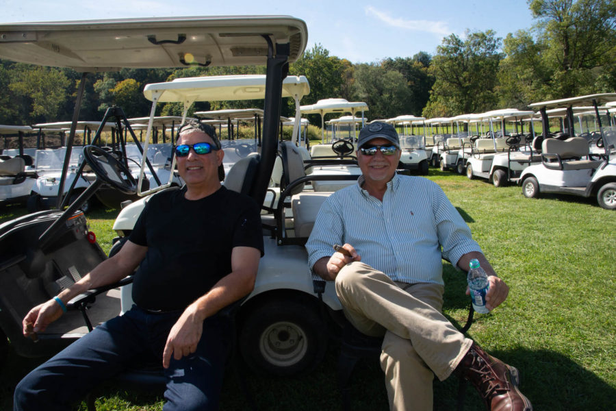 Two people relaxing by parked golf carts