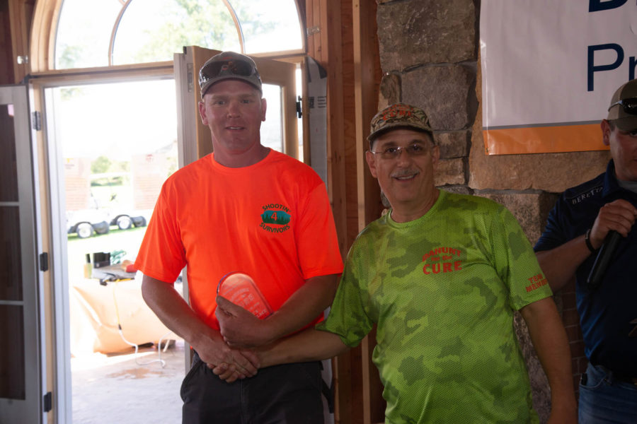 Two men indoors holding circular award