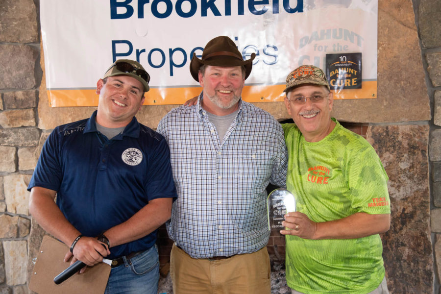 Three smiling men posing with trophy