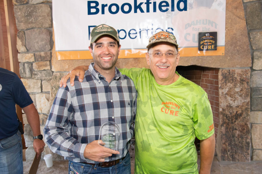 Two men smiling, one holding an award