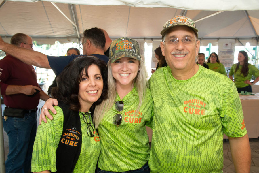 Three smiling volunteers in green "CURE" shirts