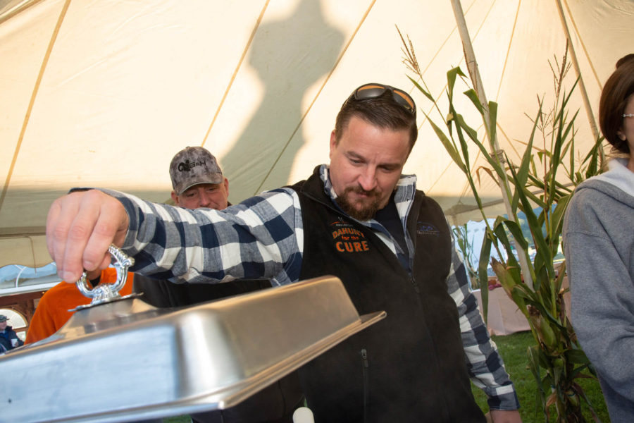 Man opening chafing dish at outdoor event