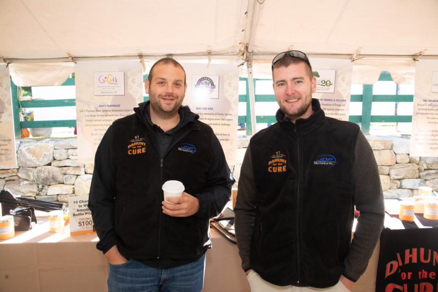 Two men smiling at outdoor vendor booth