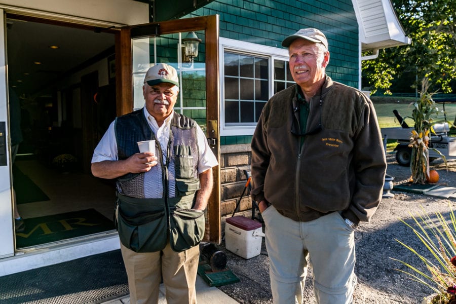 Two men standing outside beside open doorway