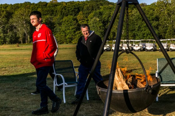Two men walking past outdoor fire pit