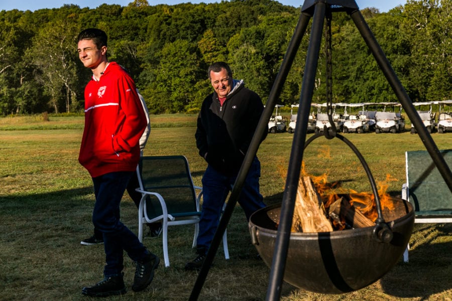 Two men walking past outdoor fire pit