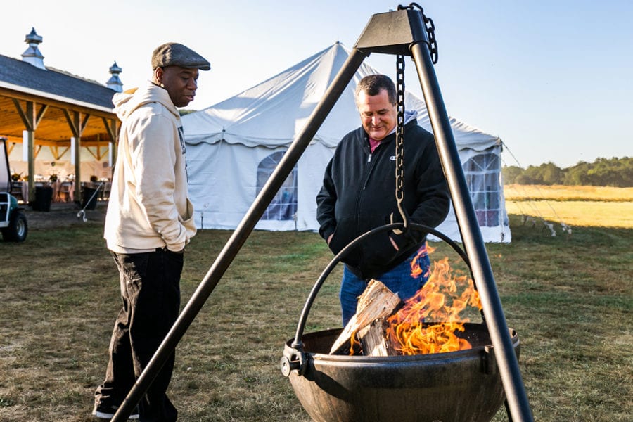 Two men warming hands at outdoor fire pit
