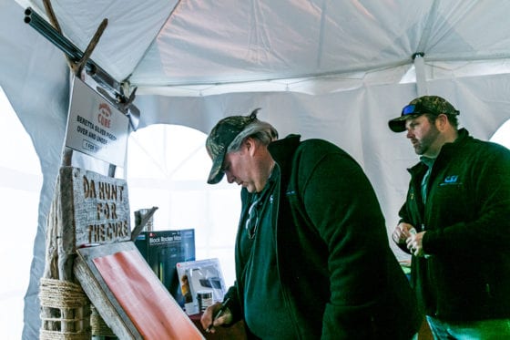 Man signing at booth while another watches