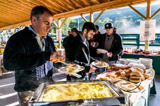 Men serving breakfast buffet under wooden pavilion