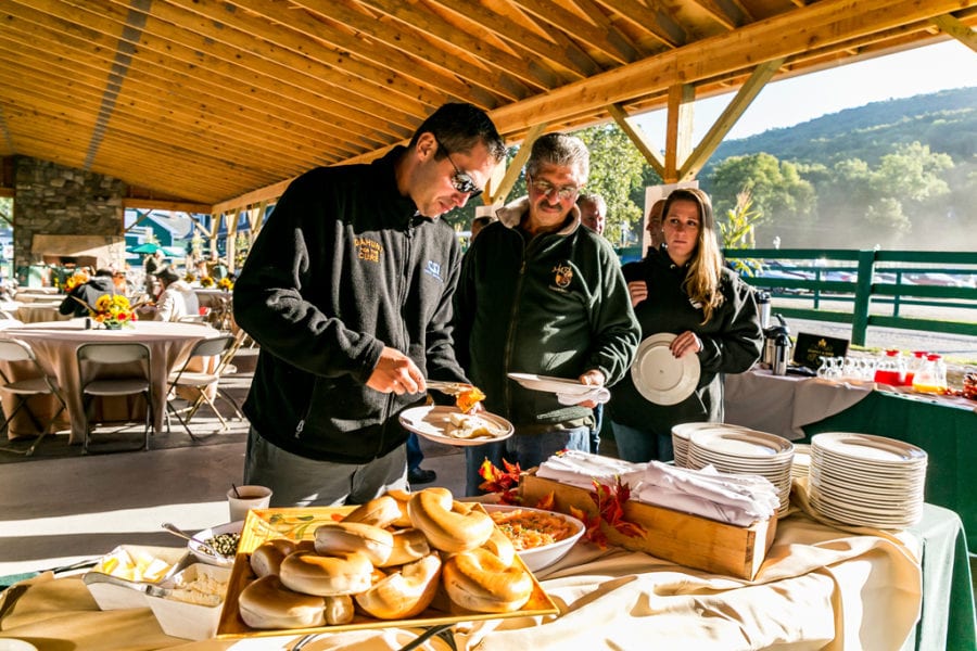 People serving themselves breakfast at outdoor buffet