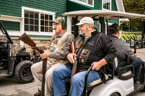 Two men with shotguns riding golf cart