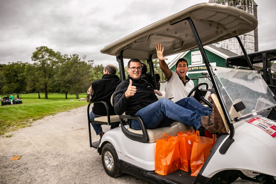 Two men waving from golf cart