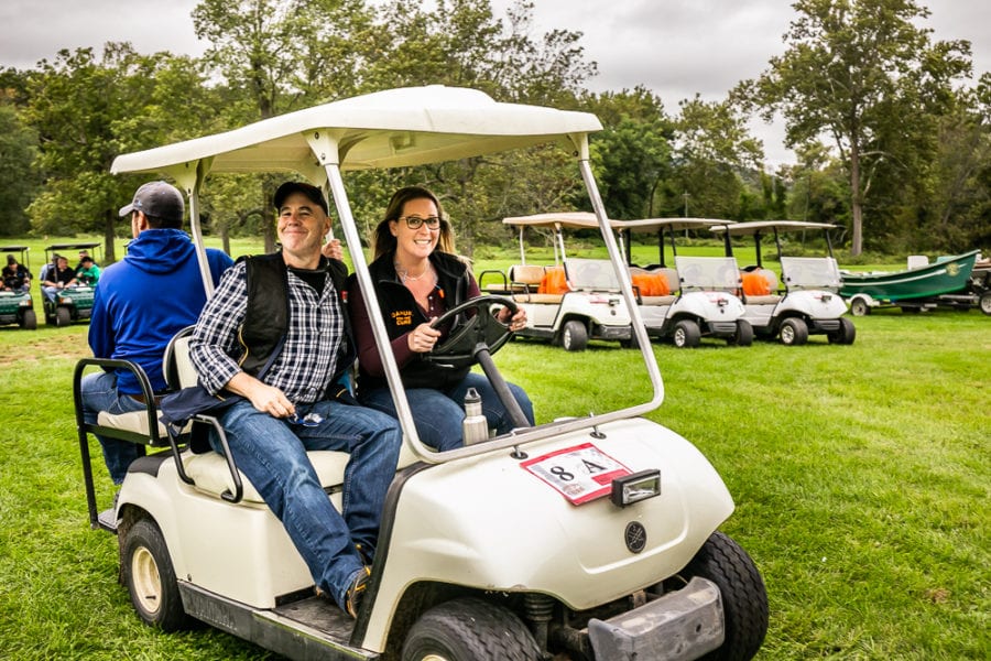 Two people smiling in golf cart on grass